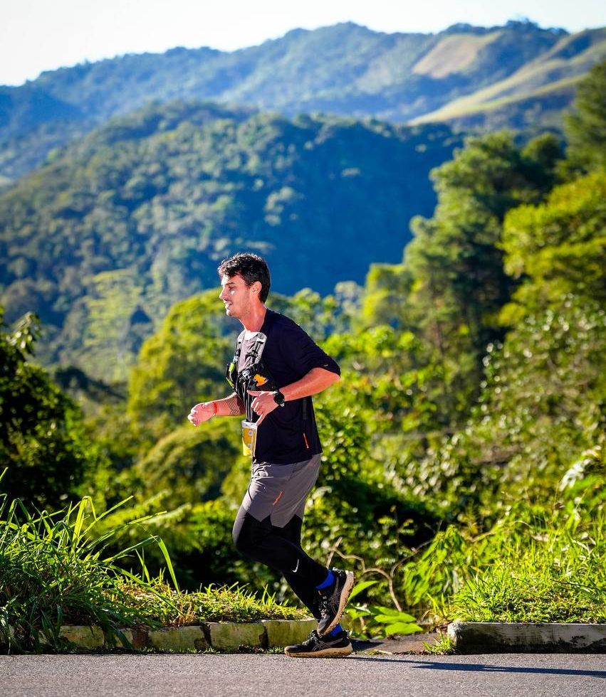 Running along a mountain road during a trail race, with layered green ridgelines in the background